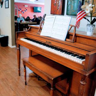 A wooden piano with sheet music displayed on the stand, accompanied by a small American flag.