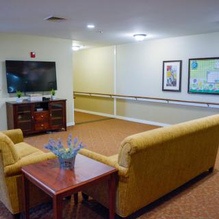 A cozy living room area with a sofa facing a television, complemented by artwork and decor.