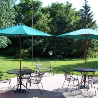 A serene outdoor patio with tables, chairs, and umbrellas overlooking a lush garden.