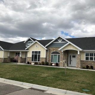 A suburban single-story house with a well-maintained lawn under a cloudy sky.