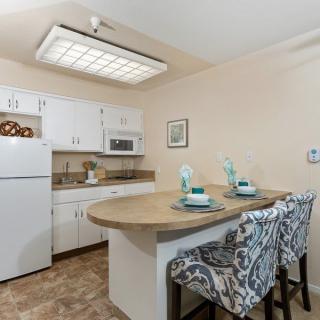 A modern kitchen with white cabinets, a central countertop, and stylish bar stools.