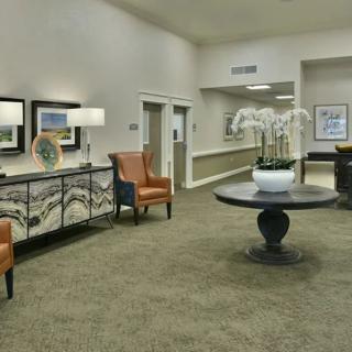 A well-decorated lobby area featuring comfortable chairs, a central table with a potted plant, and elegant lighting.