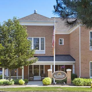 A brick building with a flagpole and landscaped entrance.