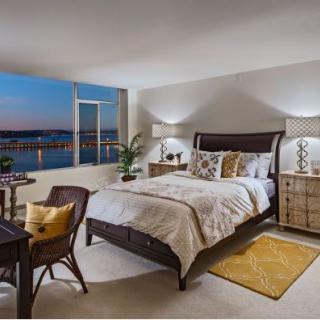 A modern and cozy bedroom with stylish furniture, featuring a stunning nighttime view through the large window.