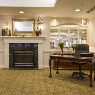 A well-furnished office space featuring a desk, a fireplace, and decorative elements.
