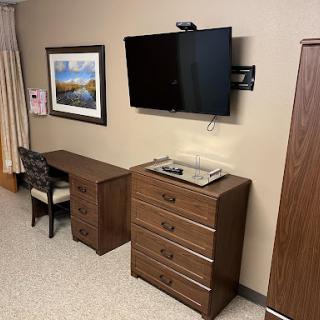 A cozy room setup featuring a television, dresser, and a desk with artwork on the wall.