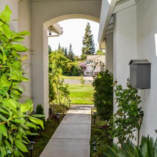 A narrow walkway with greenery and an archway leading to a residential area.