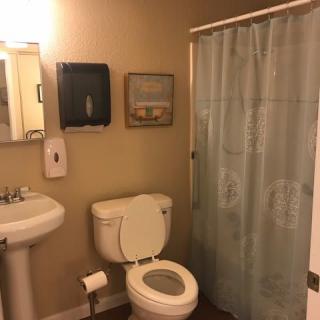 A clean and organized bathroom with a toilet, sink, and shower.