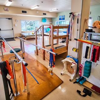 A rehabilitation center equipped with parallel bars and exercise equipment for physical therapy.