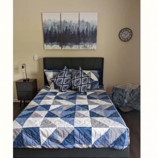 A stylish bedroom with a blue and white geometric quilt, matching pillows, and wall art decor.
