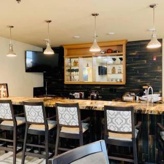 A modern indoor bar area featuring a sleek countertop, stylish seating, and ambient lighting.