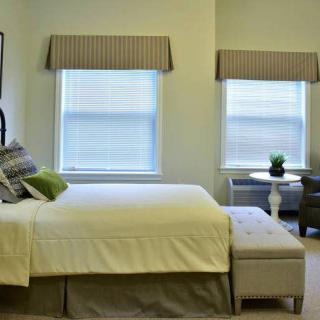 A cozy bedroom with a large bed, neutral decor, and two windows.