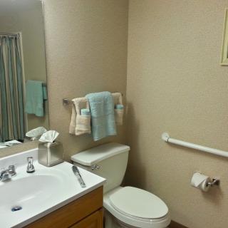 A clean and organized bathroom with a sink, toilet, mirror, and towels.