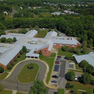 Aerial view of a school surrounded by trees and parking area.