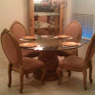 A cozy dining area with a glass-top table and four upholstered chairs.