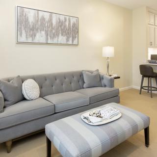 A modern living room with a gray sofa, striped ottoman, and elegant decor.