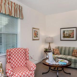 A cozy living room featuring a patterned armchair, striped sofa, and a classic coffee table with decorative items.