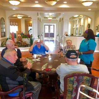 A group of seniors engaging in a conversation with a caregiver at a nursing home.
