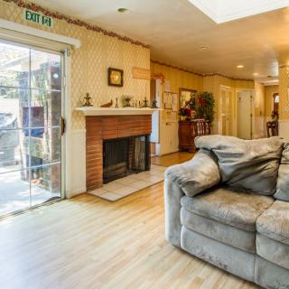 A cozy living room with a fireplace and comfortable couch, featuring wood flooring and a sliding glass door.