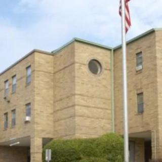 A brick building with an American flag in front on a clear day.