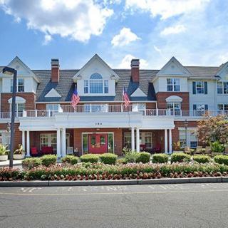 A picturesque residential building with flags displayed at the entrance and a well-maintained garden.