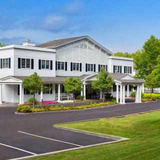 A well-maintained building with a spacious parking lot, surrounded by trees and landscaping on a clear day.