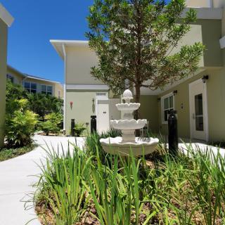 A serene courtyard with a central fountain surrounded by greenery and modern buildings.