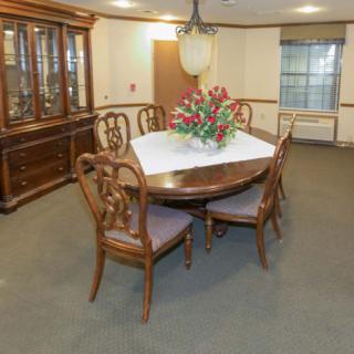 A formal dining room featuring a wooden table with chairs, a chandelier, and a display cabinet.