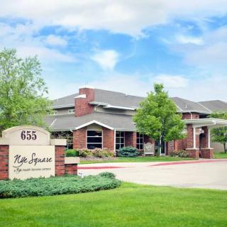 A brick building surrounded by greenery with a sign displaying the address and name of the establishment.