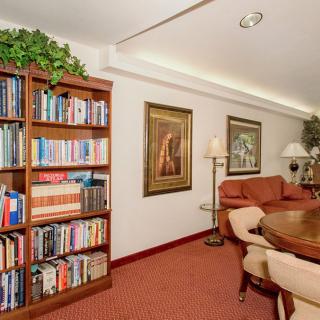 A cozy living room with a large bookshelf, comfortable seating, and decorative artwork on the walls.