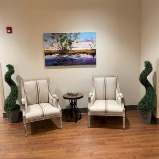 A cozy seating area featuring two stylish chairs, a small table, and decorative plants.