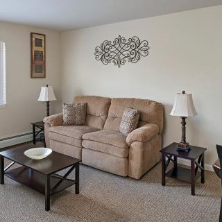 A cozy living room with a beige sofa, two matching end tables and lamps, a coffee table, and decorative wall art.