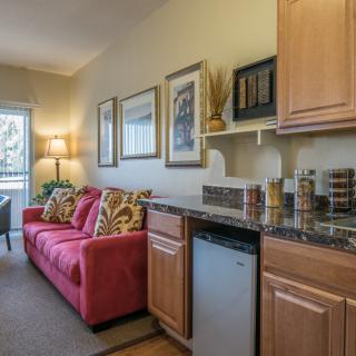 A cozy living area with a red sofa, kitchenette, and wall art in an apartment.