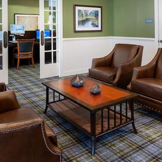 A cozy waiting room with leather chairs and a wooden coffee table, featuring a plaid-patterned carpet.