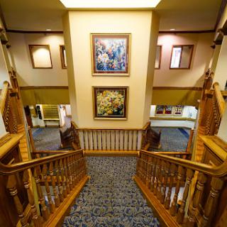 A beautifully designed interior staircase with wooden railings and framed paintings on the wall.
