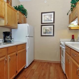 A cozy kitchen with wooden cabinets, featuring a refrigerator, stove, and coffee maker.