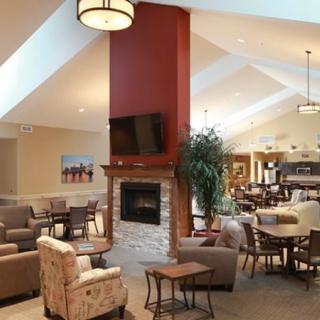 A modern living room with a central fireplace, ample seating, and a television mounted above the mantel.