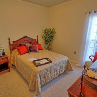 A cozy bedroom with a neatly made bed, warm lighting, and tasteful decor.