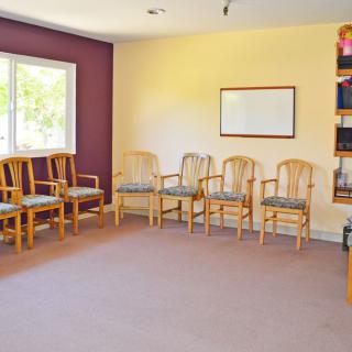 An empty waiting room with arranged chairs and a window.