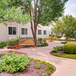 A peaceful garden area with benches and a well-maintained pathway surrounded by lush greenery.