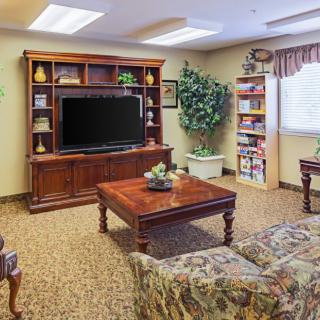 A cozy living room with a television, bookshelves, and comfortable seating.