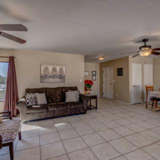 A cozy and well-lit living room featuring a comfortable sofa, ceiling fan, and dining area.