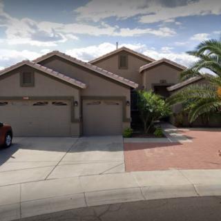 A residential house with a three-car garage and a palm tree in the front yard.