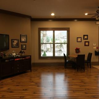 A cozy living room with hardwood flooring, featuring a window, furniture, and decorative wall art.