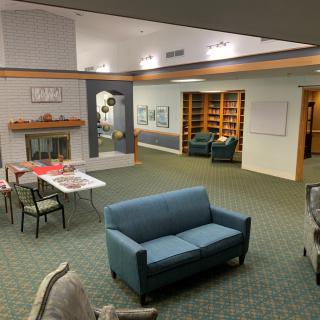 A cozy lounge area with sofas, chairs, a table, and a fireplace, surrounded by bookshelves.