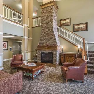 A cozy hotel lobby with a fireplace, seating area, and a staircase.