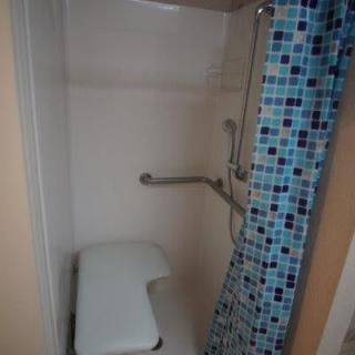 An accessible shower with a bench seat and safety grab bars.