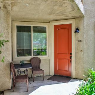 A cozy front porch with a red door and patio furniture.
