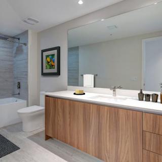 A modern bathroom featuring a wooden vanity with a large mirror, bathtub, and elegant decor.