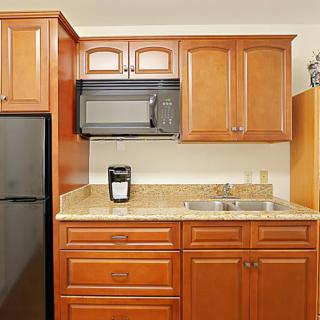 A modern kitchen with wooden cabinets, a microwave, refrigerator, and sink.